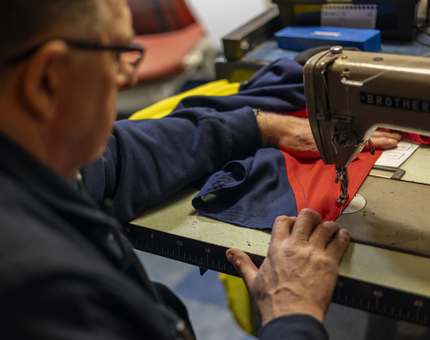 A close look at a man using a sewing machine to make dress flags for Britannia. 