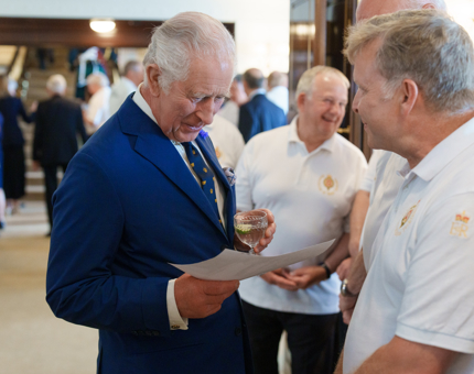 HM The King looking at a picture while speaking with Yotties. 
