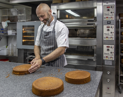A Chef cutting out sponge in the Galley for a Victoria sponge cake.