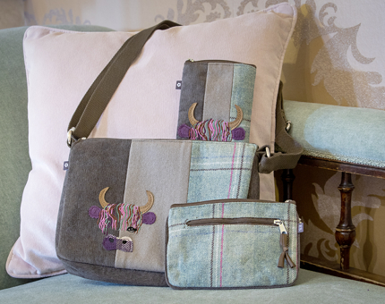 A brown and green handbag with an embroidered Highland Cow head, small green tartan zip purse and glasses case.