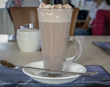 A tall glass of hot chocolate with marshmallows on top.