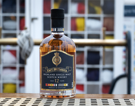 A bottle of Britannia whisky with flags in the background.