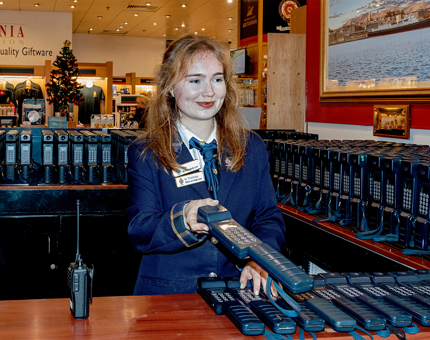 A woman giving an audio handset to a visitor in the Visitor Centre.