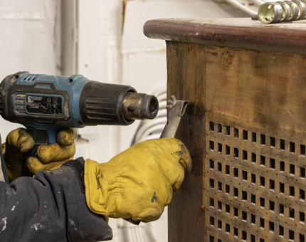 A heat gun removing varnish from a wooden rope box. 