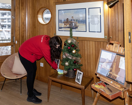 A Housekeeper polishing around the miniature Christmas tree in the Sun Lounge.