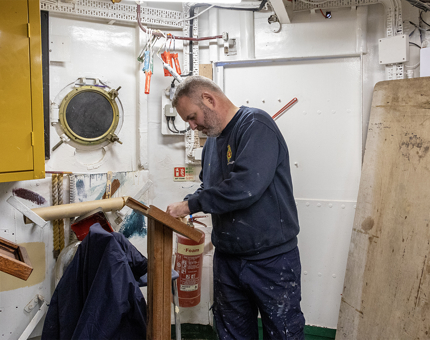 A Maintenance team member preparing to varnish the refurbished wooden menu stands. 