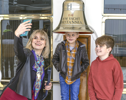 A woman and two boys take a selfie in front of Britannia's Bell. 