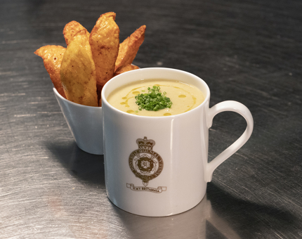 Soup in a Britannia crested mug and a dish of paprika potato wedges.