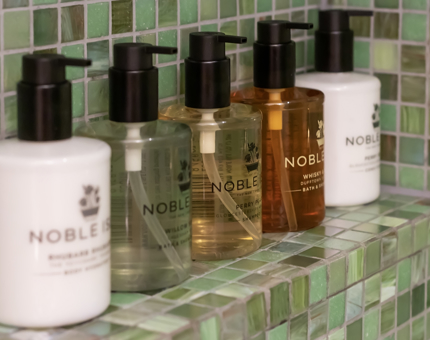 Five bottles of Noble Isle toiletries on a shelf in a cabin bathroom at Fingal. 