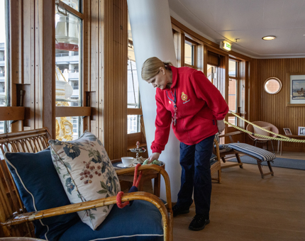 A Housekeeper dusting the bamboo furniture in the Sun Lounge.