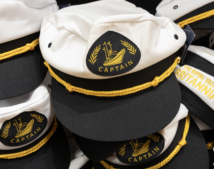 A display of novelty children's Captain hats. They have a navy blue peak, white top, Captain badge and yellow embroidered rope. 
