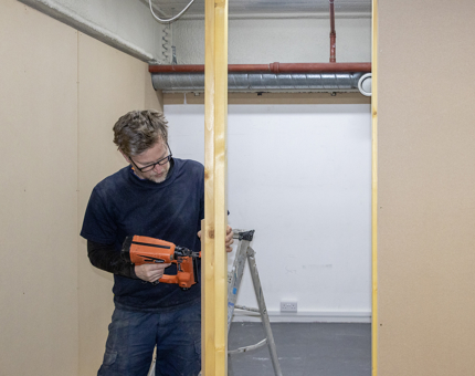 A man from Maintenance creating a wooden partition in the temporary Gift Shop.