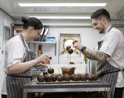 Two Chefs working in the Galley creating chocolate desserts.