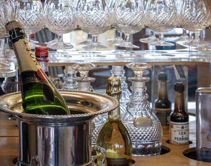 A drinks cabinet containing many glasses and an ice bucket with a bottle of Champagne.