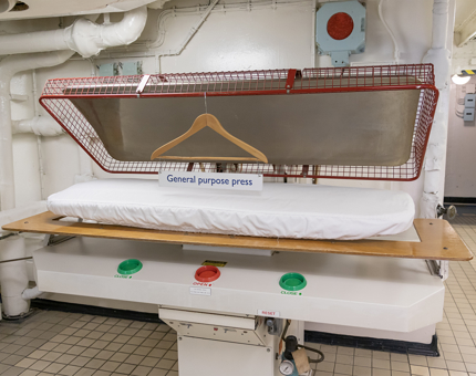 A large press machine in the onboard Laundry.