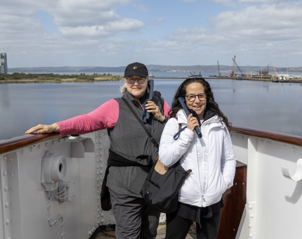Two ladies listening to audio guides on an outside deck on Britannia. 