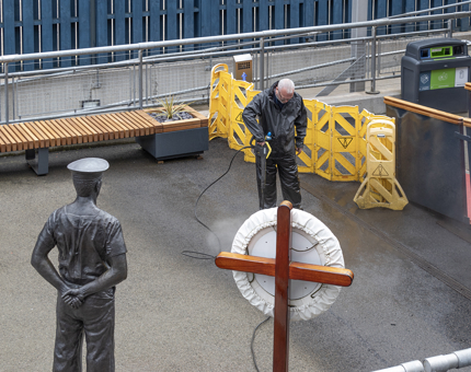 A member of the Facilities team power washing the compound outside Britannia. 