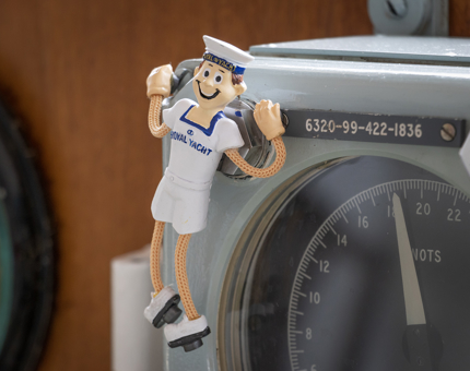 A novelty Yottie dangler fridge magnet wearing a white t-shirt and shorts.