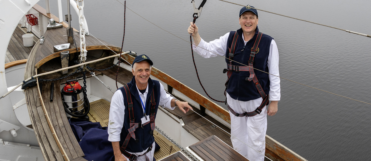 Two Yotties standing smiling while standing in one of Britannia's Whaler boats. 