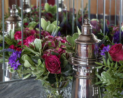 Mirrors reflect a bunch of flowers and a silver cocktail shaker shaped like a lighthouse