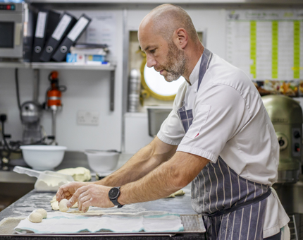 A Chef making bread rolls in the Galley. 