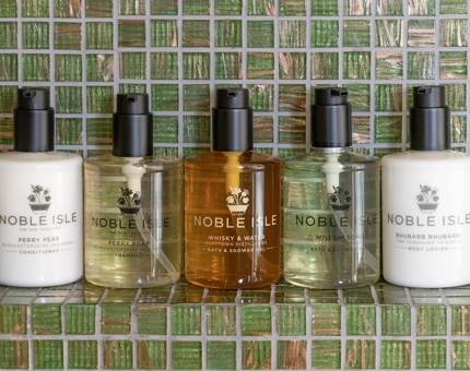 A row of Noble Isle luxury bath and body products sitting on a shelf in a Fingal cabin bathroom. 