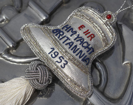 A silver fabric embroidered hanging decoration in the shape of Britannia's Bell.