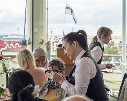 Servers attending to visitors sitting at tables in the Tearoom. 