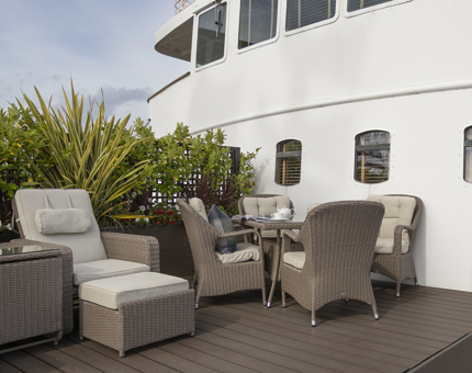 The private deck of the Skerryvore Suite on Fingal. There are sunloungers and a table with chairs. 