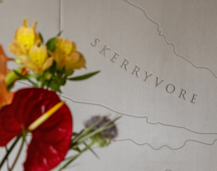 The decorated headboard in Skerryvore with brightly coloured vase of flowers in the foreground. 