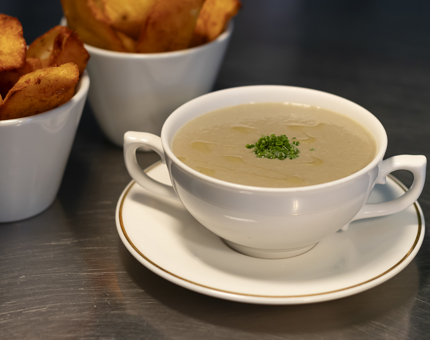 A bowl of soup with a dish of potato wedges.