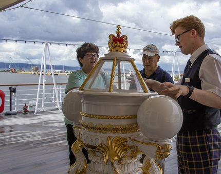 A Visitor Assistant is chatting with two visitors at the Compass Binnacle. 