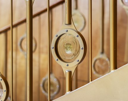 A detail of the golden staircase with bulls-eye glass stair rods.