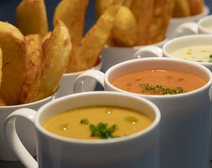 Mugs of soup and potato wedges. 