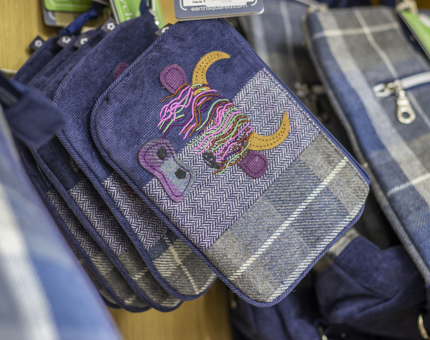 A tartan purse with an embroidered image of a highland cow