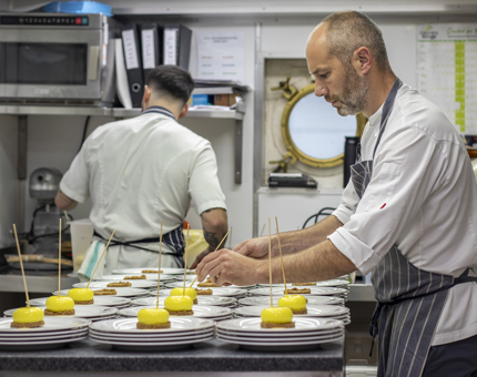 Two male chefs in the Galley preparing lemon cheesecakes.