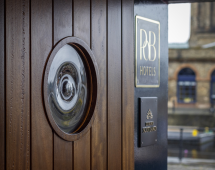 A close up of a wooden door with a circular window.