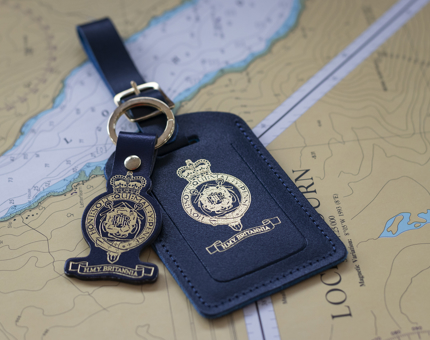 A blue luggage tag with a gold Britannia crest on it. 
