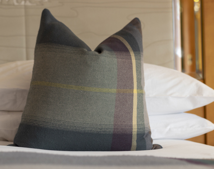 A tartan pillow on a bed. 