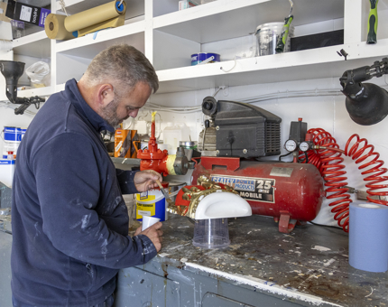 A man wearing a blue jumper painting a crown mold. 
