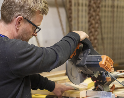 A man cutting a piece of wood. 