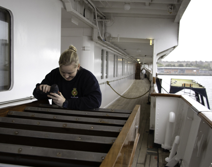 Woman holding drill works on screwing steel fronts onto a ladder.