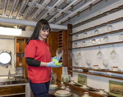 A member of the Housekeeping team polishing glassware in the pantry.