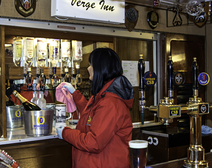 A housekeeper polishes the optics at The Verge Inn bar, inside The Petty Officer's and Royal Marines Sergeants' Mess.