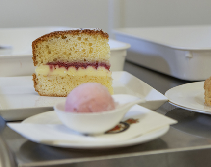 A slice of Victoria Sponge and a scoop of strawberry ice cream.