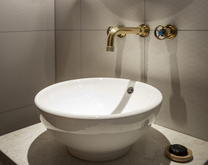 Details of a white sink with a nautical style brass tap. 