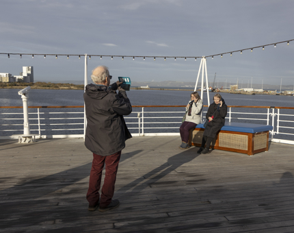 A man taking a photo on the Verandah Deck on a sunny day.