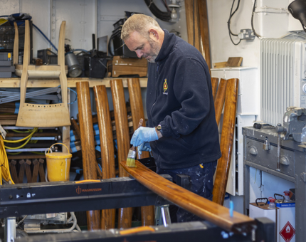 A man varnishing a handrail. 