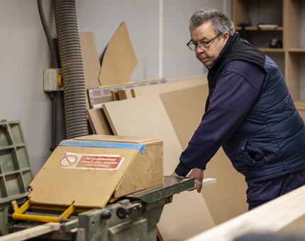 A Maintenance team member putting wood through the planer. 
