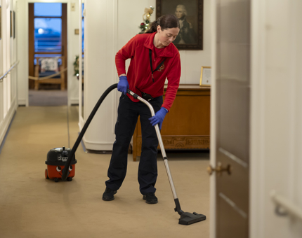 A Housekeeper hoovering the carpet.